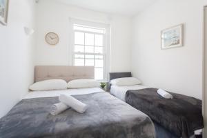 Un dormitorio con dos camas y un reloj en la pared. en Camden House - Next to Camden Market and Station - City Center, en Londres