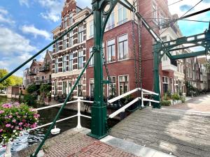 eine grüne Brücke über einen Fluss mit einem Gebäude in der Unterkunft Pakasa in Leiden