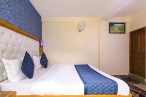 a hotel room with a bed with blue and white sheets at FabHotel Negis Shivalay in Manāli