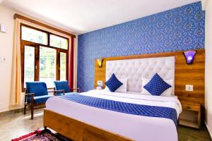 um quarto com uma cama grande e paredes azuis em FabHotel Negis Shivalay em Manali