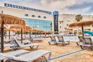 a group of chairs and umbrellas in front of a hotel at ALEGRIA Cabo De Gata in Retamar