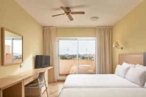 レタマルにあるALEGRIA Cabo De Gataのベッド、デスク、窓が備わるホテルルームです。