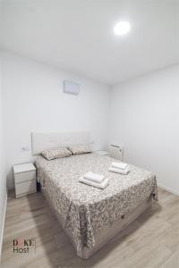 a white bedroom with a bed with two towels on it at Castellana Norte Ml8 in Madrid