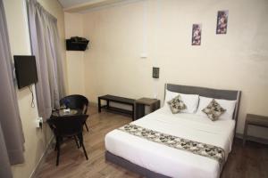 a bedroom with a bed and a table and a tv at Myra Hotel Mersing in Mersing