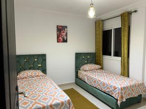 a bedroom with two beds and a window at Flowers home in Oujda