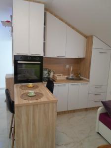 eine Küche mit weißen Schränken und einer schwarzen Mikrowelle in der Unterkunft Fine Rest Brcko 2 in Brčko