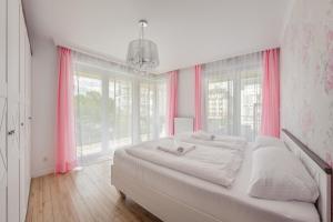- une chambre avec un grand lit et des rideaux roses dans l'établissement Apartamenty Sun & Snow Promenada II, à Świnoujście