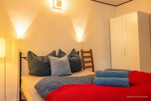 um quarto com uma cama com almofadas azuis e um cobertor vermelho em FEWO in Weimar mit Garten am Schwanseebad em Weimar