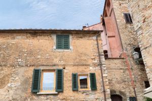 un vecchio edificio con persiane verdi di Losanna Suites a Campiglia Marittima