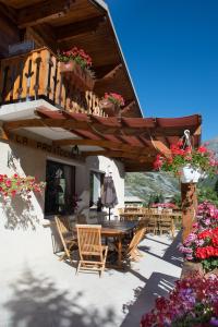 a patio with a wooden table and chairs and flowers at B&B Chalet La Providence in Le Sauze