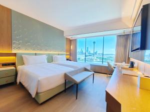 um quarto de hotel com uma cama grande e uma janela grande em YOHO Treasure Island Hotel em Macau