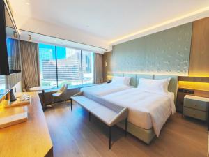 ein Hotelzimmer mit einem großen Bett und einem Schreibtisch in der Unterkunft YOHO Treasure Island Hotel in Macau