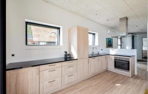 eine große Küche mit weißen Wänden und Holzschränken in der Unterkunft Lovely Home In Brkop With Wifi in Børkop