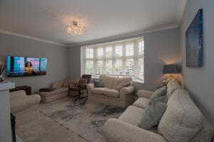 a living room with couches and a tv at Elegant and spacious private room with ensuite in Luton
