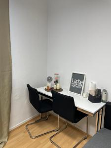 una mesa blanca con 2 sillas y un ordenador portátil. en SleepWellCologne en Colonia