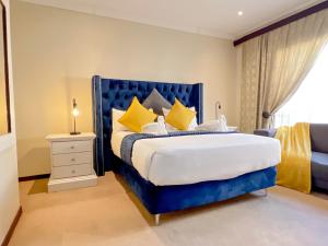 a bedroom with a blue bed with yellow pillows at Covesto Guesthouse - Waterkloof in Pretoria