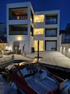 a building with a boat in the water in front of it at Villa Muzo in Betina