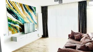 Apartament Dem Rădulescu Lidl في رمينكو فيلتشا: غرفة معيشة مع أريكة ولوحة على الحائط