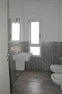 a bathroom with two sinks and a toilet and two mirrors at BoaOp Apartaments in Sal Rei