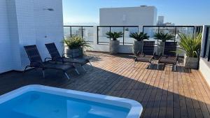 a balcony with chairs and a swimming pool on a building at Ap 2 dormitórios com piscina a 4 quadras do mar Le Monde in Capão da Canoa