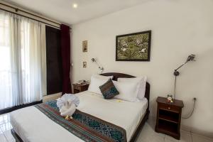 een slaapkamer met een bed, 2 tafels en een raam bij Manzelejepun Luxury Villa & Pavilion in Sanur