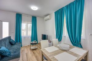 uma sala de estar com cortinas azuis e uma mesa em Apartment Porec-Jug em Porec