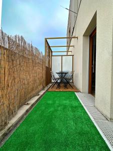 a patio with a green floor in a house at L'envolée - 15' de Paris & 10' du Stade de France in Saint-Denis