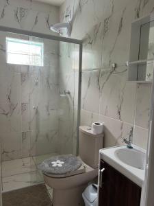 een badkamer met een toilet, een wastafel en een douche bij Hostel Jardim de Lotus in Blumenau