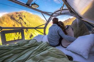 een stel in een tent met uitzicht op de bergen bij Skylodge Adventure Suites in Urubamba