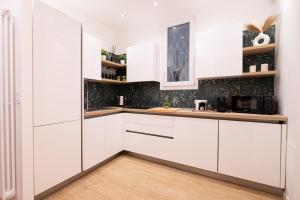 a white kitchen with white cabinets and a wooden floor at Domus Vatican Holiday in Rome