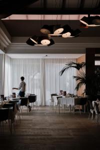 a man standing in a dining room with tables and chairs at Prinsotel La Dorada & Spa in Playa de Muro