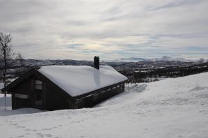 a snow covered cabin on top of a snow covered hill at Veslestølen - Ålhytte with amazing view, 1000 meter in Ål