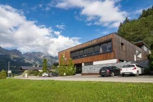 una casa con dos coches estacionados frente a ella en Alpensuiten en Ellmau