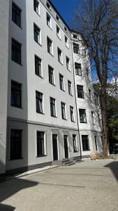 a large white building with a tree in front of it at BDSM Red Room Apartment in Łódź