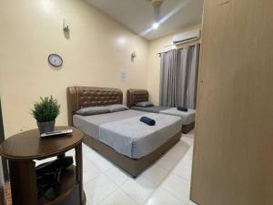 1 dormitorio con 2 camas, mesa y reloj en Redzuan Homestay (Muslim Friendly) en Muar