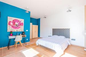 Schlafzimmer mit blauen Wänden, einem Bett und einem Schreibtisch in der Unterkunft Logis de beauce 