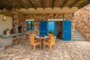 a patio with a table and chairs and a stone wall at Fattoria delle Ripalte in Capoliveri +17 photos