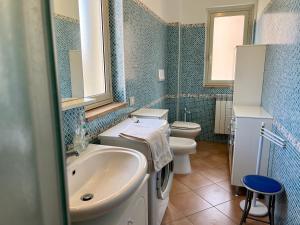 baño de azulejos azules con lavabo y aseo en Oliveri nuovo appartamento 5 posti letto più posto auto privato, en Oliveri