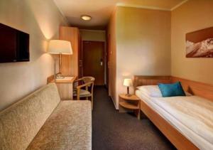 une chambre d'hôtel avec un lit et un canapé dans l'établissement Hotel FIS, à Štrbské Pleso