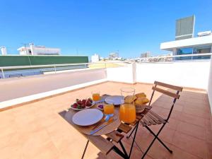 einen Tisch mit Gläsern Orangensaft und Obst auf dem Dach in der Unterkunft Lovely Terrace Studio Baixa Faro in Faro