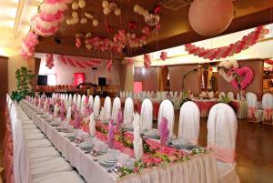 a long banquet table with white and pink decorations at Hotel Maggi in Rogoźno +14 photos