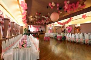 un salón de banquetes con mesas, sillas blancas y globos rosados en Hotel Maggi, en Rogoźno