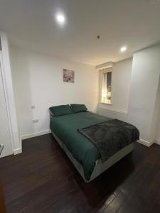 a bedroom with a bed with a green comforter and a window at Amazing 1 Bedroom Flat in Essex TH104 in Basildon