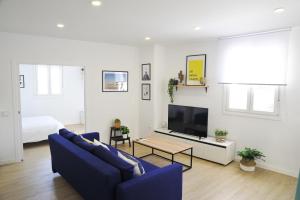 a living room with a blue couch and a tv at El Apartamento de Nueva in Cádiz
