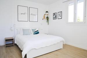 a white bedroom with a white bed and two windows at El Apartamento de Nueva in Cádiz