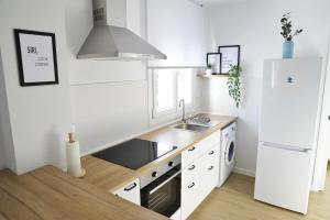 a white kitchen with a sink and a refrigerator at El Apartamento de Nueva in Cádiz