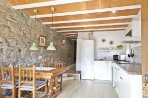 uma cozinha com uma mesa de madeira e uma parede de pedra em Mas Regort em Vallfogona de Ripolles