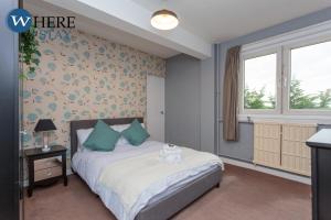 a bedroom with a bed with blue pillows and a window at Stunning 3 bedroom apartment Edinburgh in Edinburgh