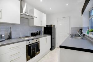 een keuken met witte kasten en een zwarte koelkast bij Sweet Home with Backyard in Howden-le-Wear for 3 in Crook