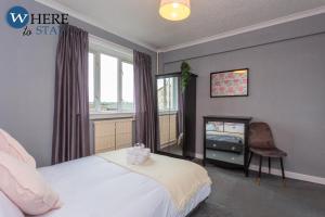 um quarto com uma cama, uma janela e uma cadeira em Stunning 3 bedroom apartment Edinburgh em Edimburgo